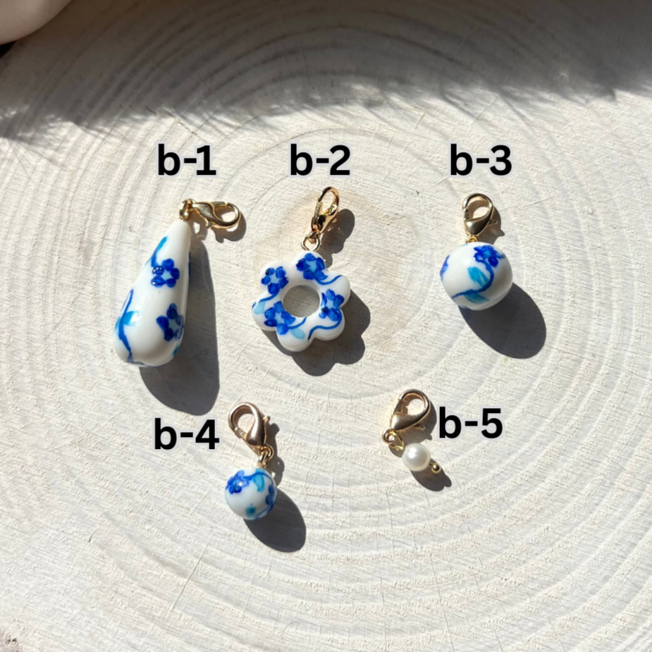Set of five small decorative items with blue floral designs on a textured surface.