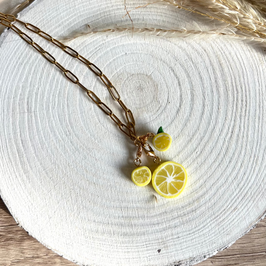 Necklace with lemon-shaped pendants on a white wooden surface